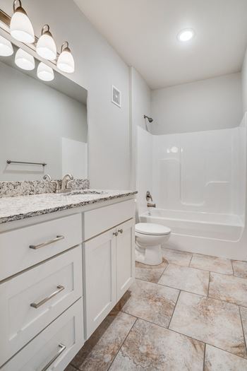 Spacious Bathroom with Granite Countertop Vanity & Tile-Style Flooring